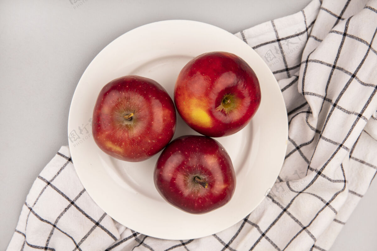 水果白色墙壁上格子布盘子上甜红苹果的俯视图农业视图顶部