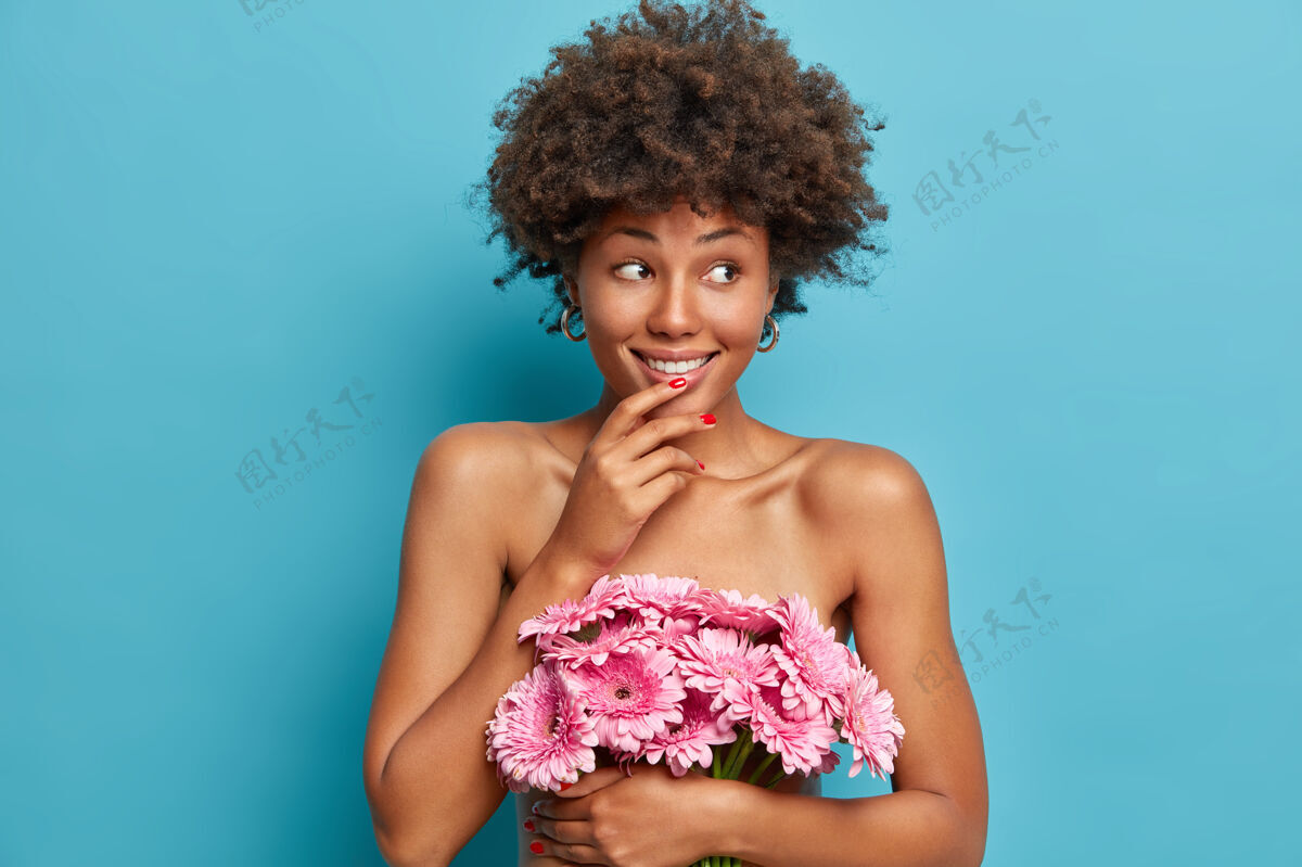 高兴性感快乐的裸体健康女模特 捧着一束粉色非洲菊花 以梦幻欢快的表情站在一旁美丽满意心情
