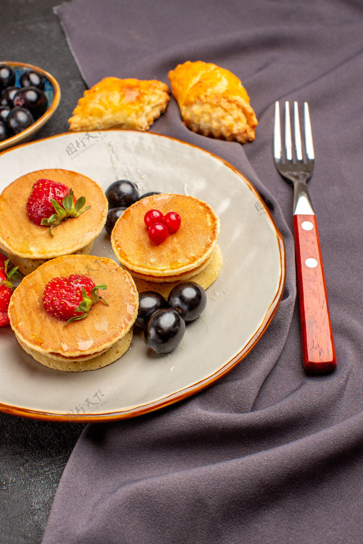 营养正面是美味的薄饼和水果和橄榄在黑暗的表面甜甜的水果蛋糕早餐膳食盘子