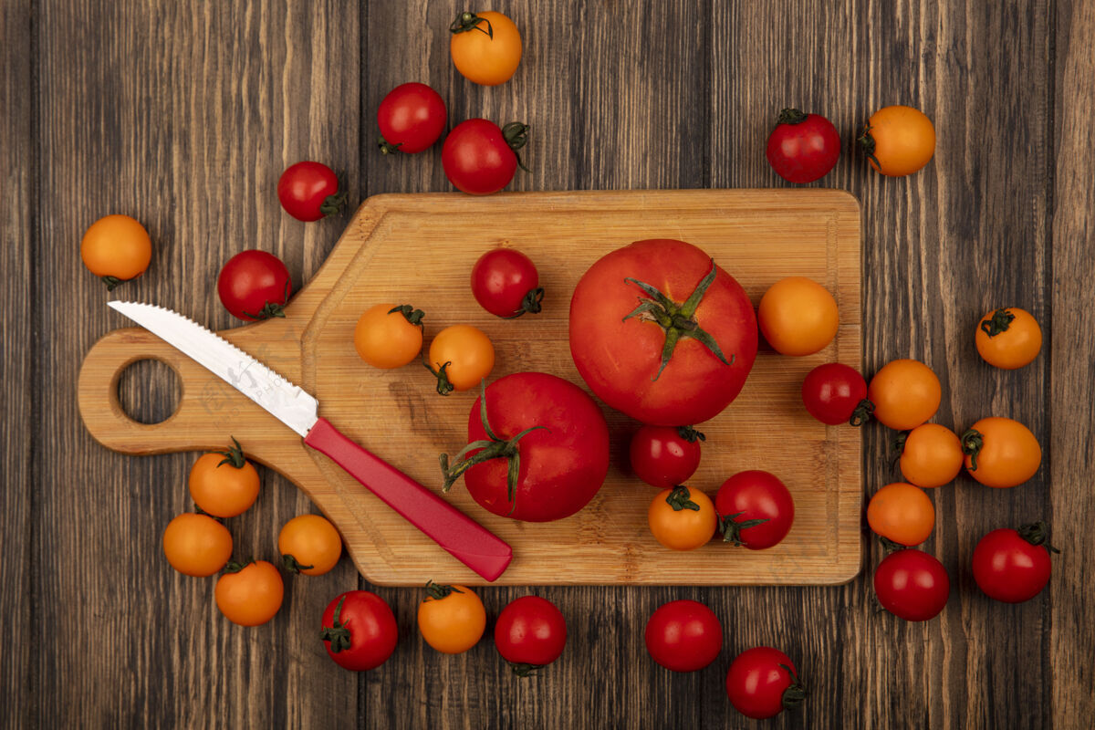 番茄新鲜的橙色和红色西红柿的俯视图被隔离在木制的厨房板上 刀子放在木制的墙上木材有机食品