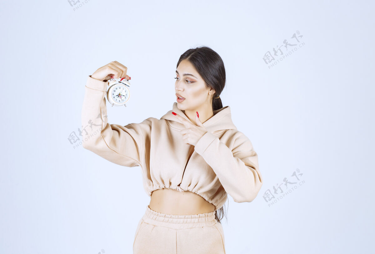 产品一个年轻的女士拿着一个新的闹钟在推销姿势商业休闲