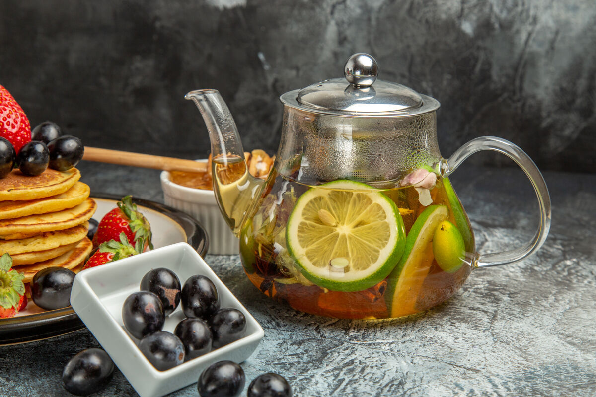 茶壶正面图美味的橄榄煎饼和茶壶上的浅色水果食品厨具茶灯