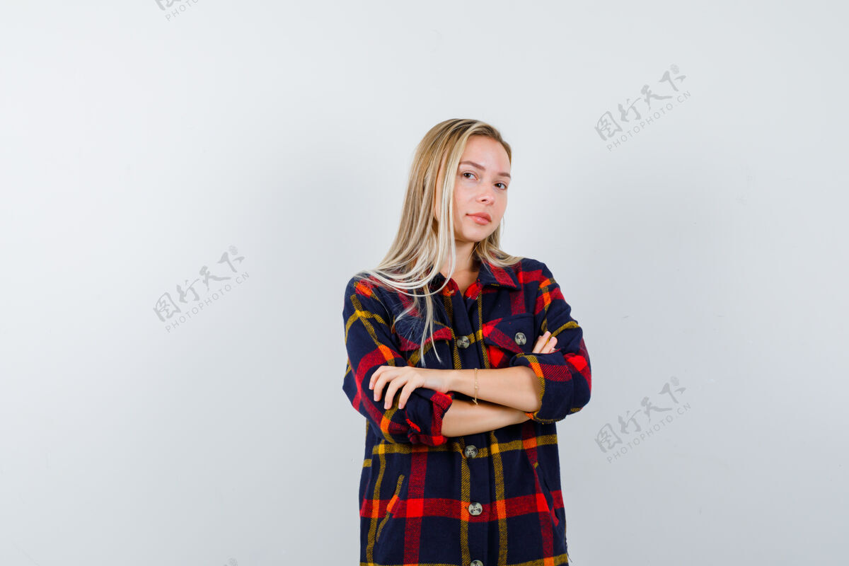时尚照片中的年轻女士交叉着双臂站在格子衬衫里 看起来很自信交叉年轻魅力