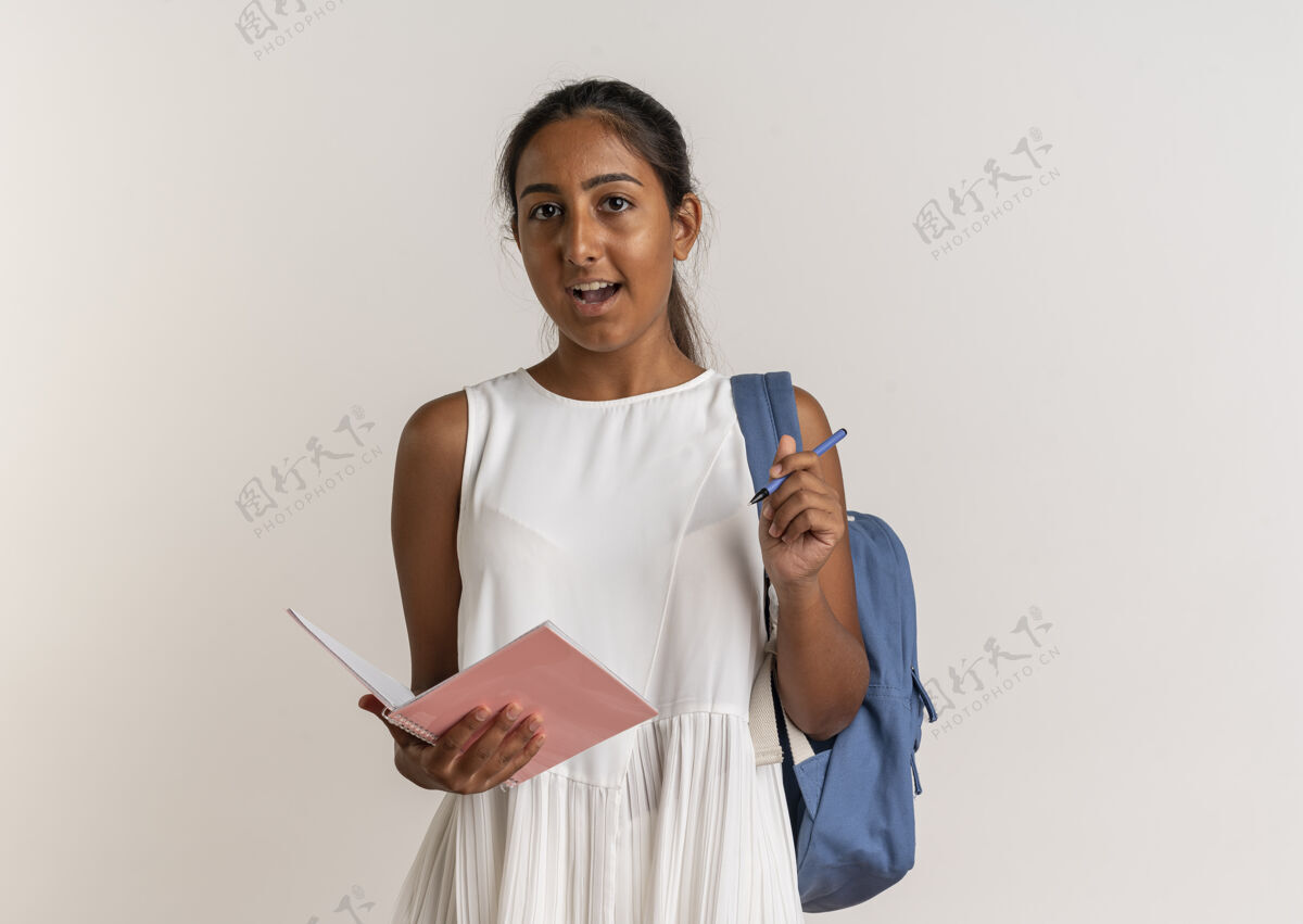 笔记本惊讶的年轻女学生背着包拿着笔记本和笔在白色的女生包背