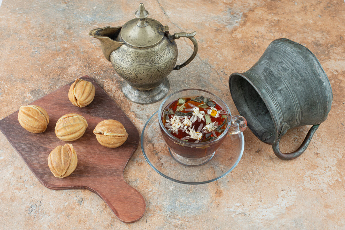 马克杯两个古老的茶壶和甜饼在大理石背景上茶壶糕点木头
