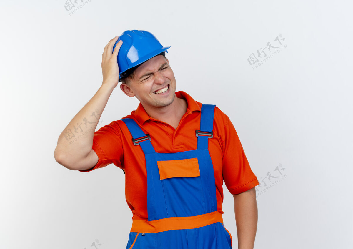 建筑工人年轻的男建筑工人穿着制服 戴着安全帽 手放在头上 戴着白色的帽子眼封闭男性