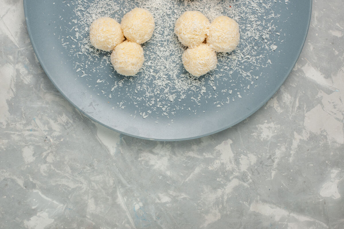 豆类白色桌子上蓝色盘子里美味椰子糖的俯视图饼干可口桌子