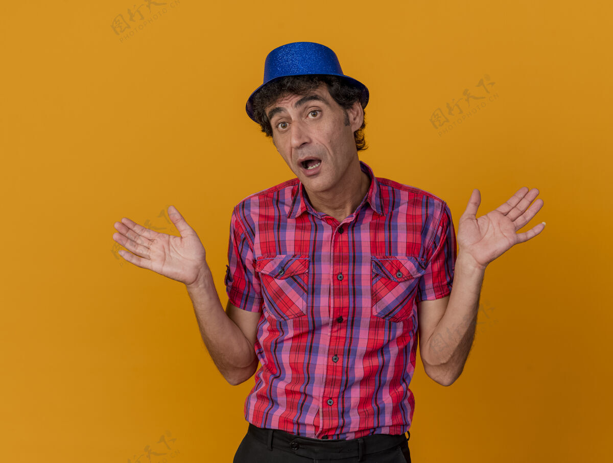 印象印象深刻的中年党人戴着党的帽子看在一边显示空的手孤立在橙色的墙上姿势人空