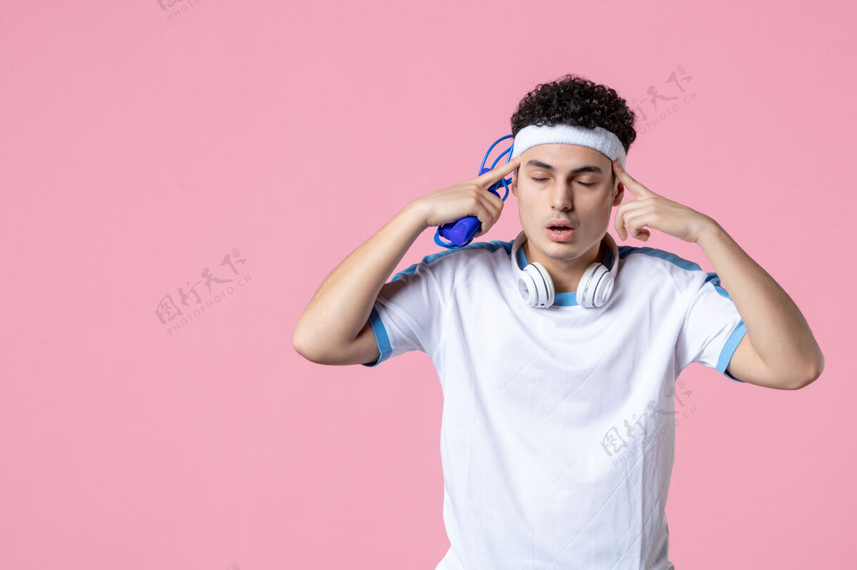 年轻正面图：穿着运动服的年轻男子跳绳绳子粉红色快乐