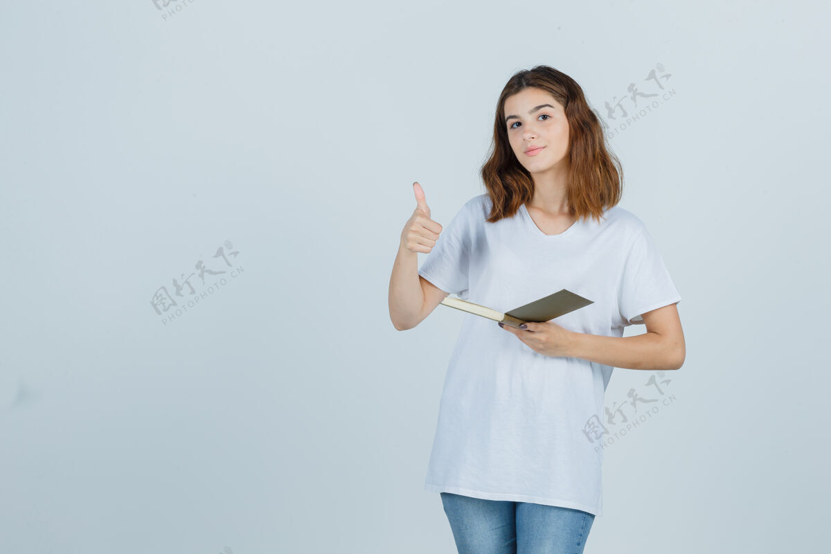 前面一位年轻女士拿着书 穿着t恤 牛仔裤竖起大拇指 看上去很开心正面图护理女士魅力