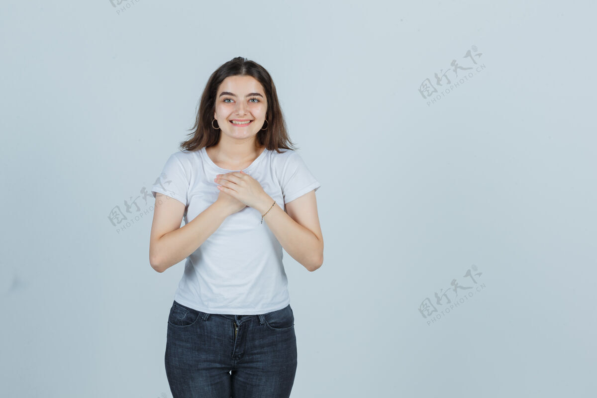 新鲜穿着t恤 牛仔裤的年轻女孩手拉着手放在胸前 看起来很可爱 前视图健康人微笑