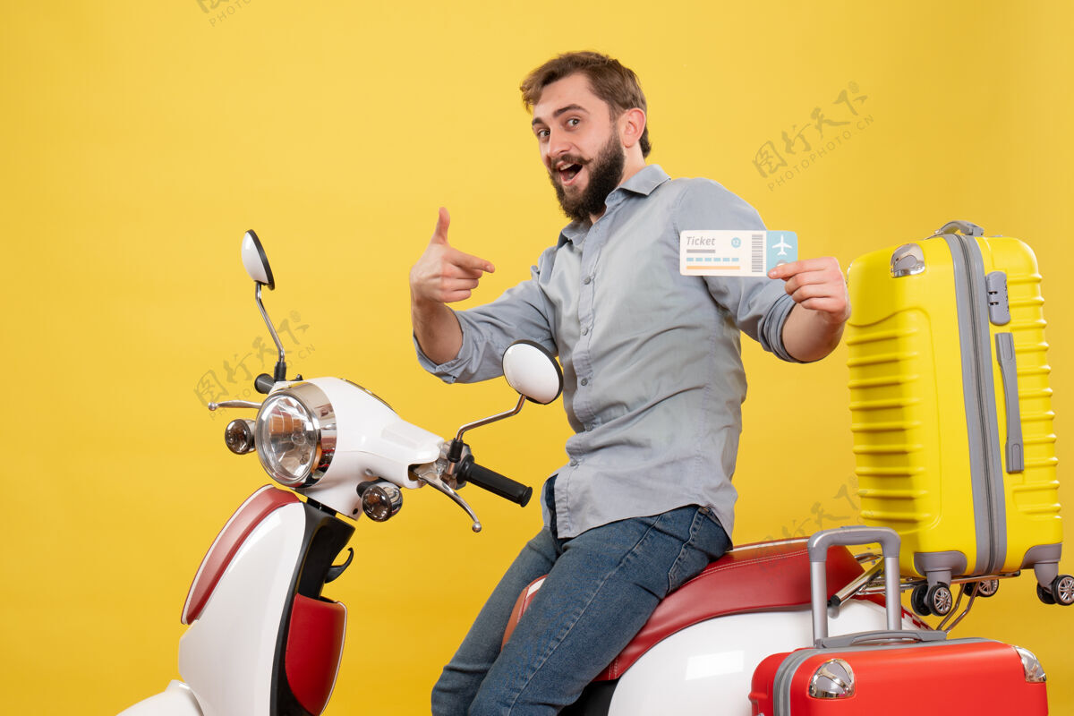 车辆旅游概念与年轻的微笑胡须男子坐在摩托车上 并指出它的黄色车票汽车摩托车旅行