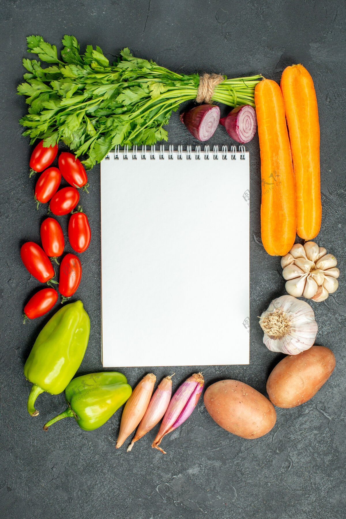 沙拉在深灰色背景上 笔记本的顶视图周围有蔬菜深色背景胡椒