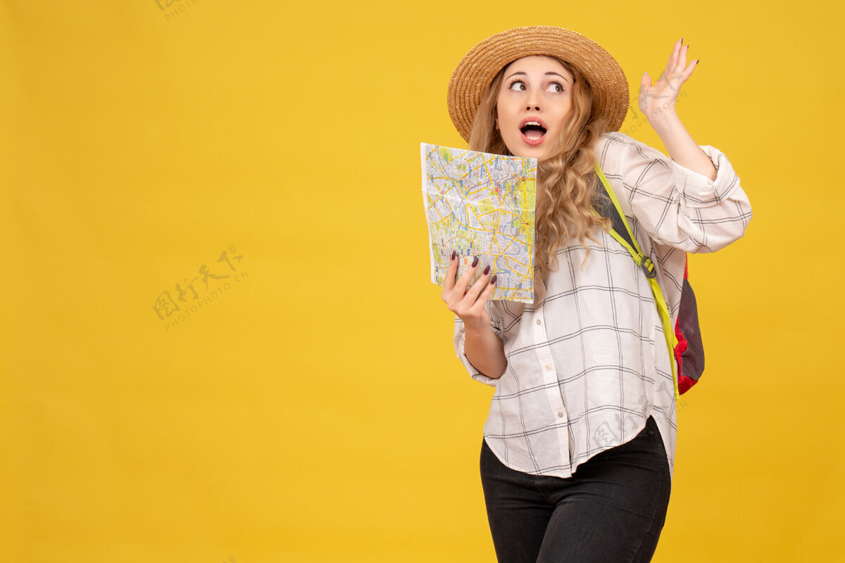 肖像顶视图好奇的旅行女孩戴着她的帽子和背包举行黄色地图背包好奇帽子