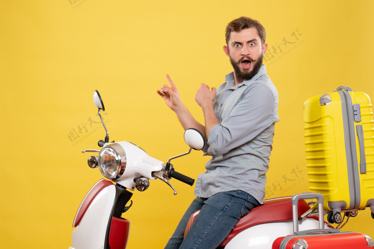 年轻人前视图的旅游概念与紧张 愤怒 情绪化的年轻人坐在摩托车与手提箱上它的黄色手提箱自行车人