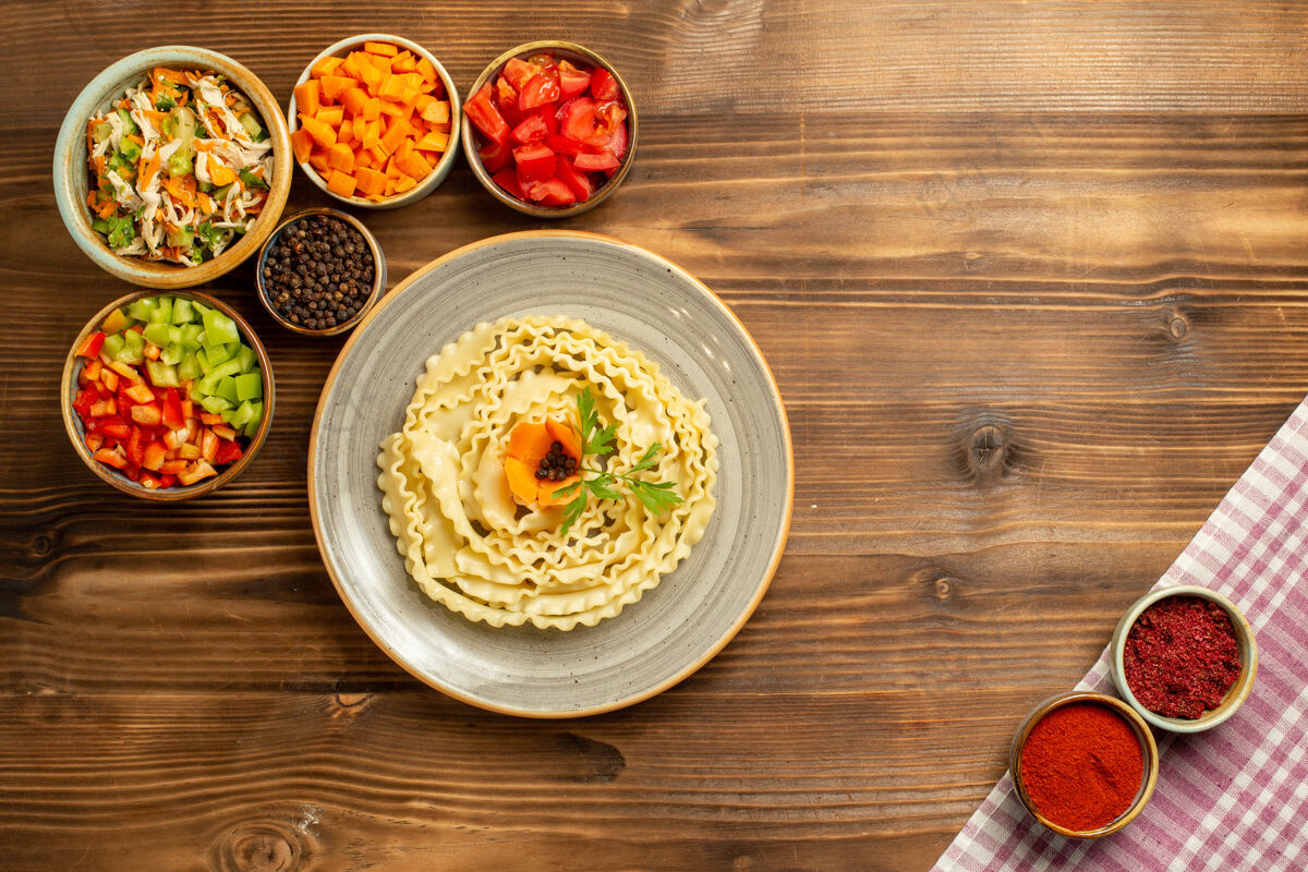 蔬菜顶视图生面团与蔬菜和调味品在棕色桌面团生食面团生的盘子晚餐