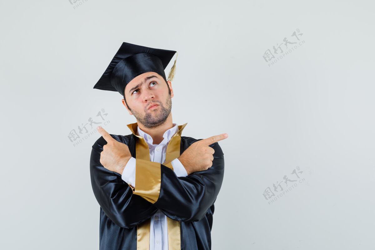 眼镜年轻人指着远处的毕业生制服 看上去犹豫不决前视图制服肖像年轻