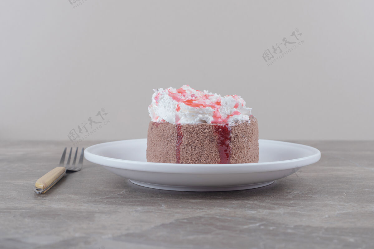 盘子一个小蛋糕 上面放着奶油和草莓糖浆 放在大理石盘子上美味糕点甜点