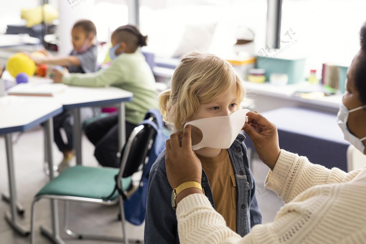 知识女老师帮孩子们戴医用口罩孩子多元文化面具