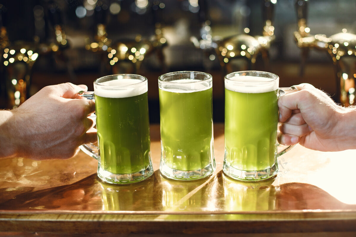 泡沫杯子里的绿色饮料男人手里的杯子酒吧里的啤酒黄金烧杯酒吧