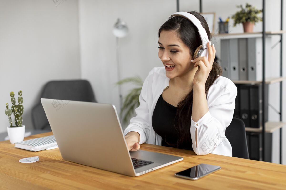 视频通话戴着耳机的中镜头笑脸女人工作中笔记本电脑专业