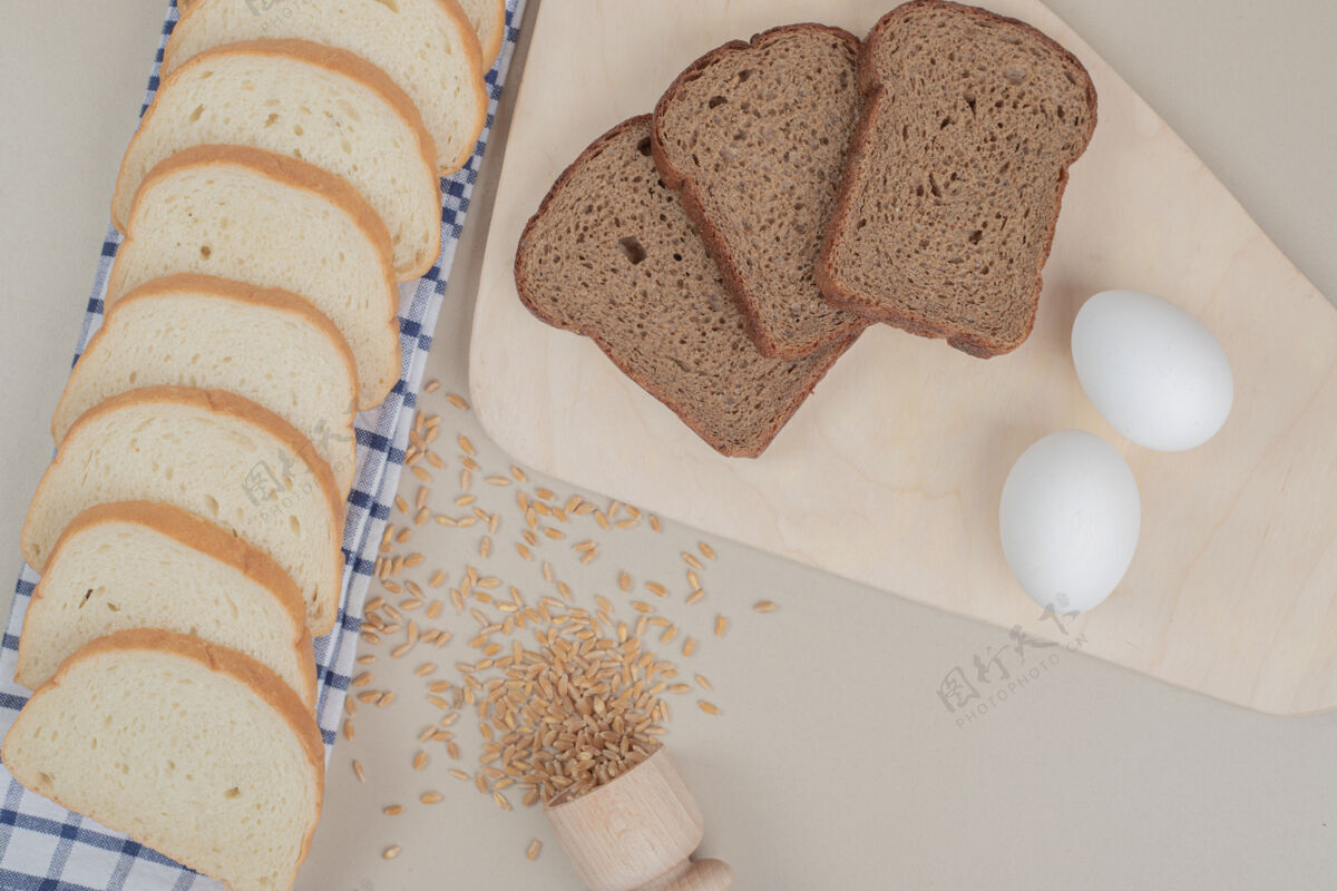 美食把新鲜的白棕色面包片和鸡蛋放在桌布上脆餐面包