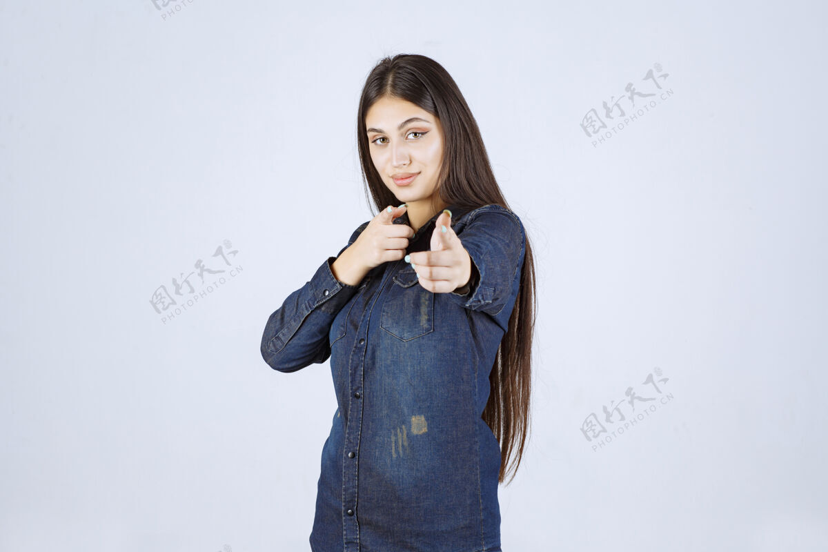 人类穿着牛仔衫的年轻女子指着她面前的人女人年轻人工人
