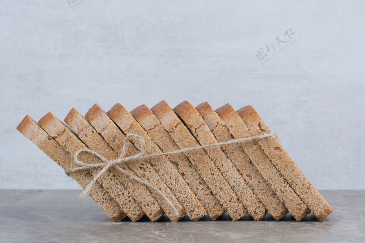 自然用绳子把棕色面包片放在大理石表面面包房食品切片
