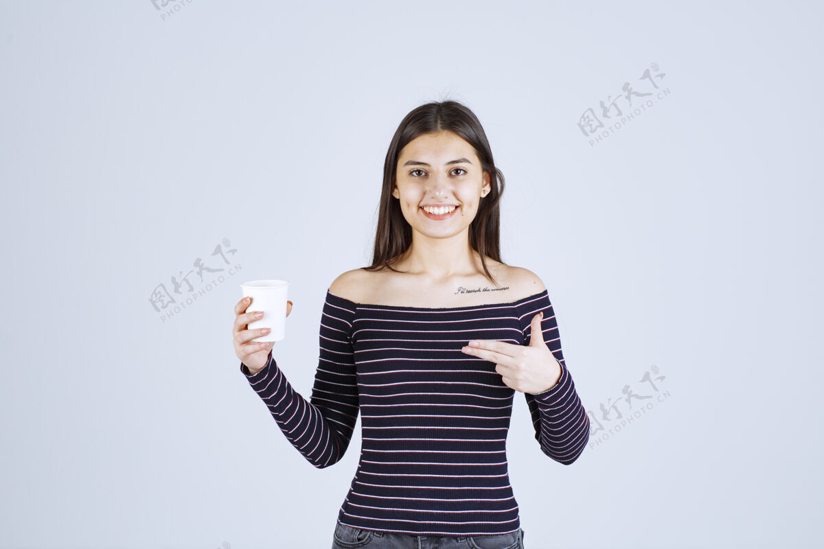 聪明人穿着条纹衬衫的女孩拿着一个塑料咖啡杯 介绍它是一种产品年轻人工人销售