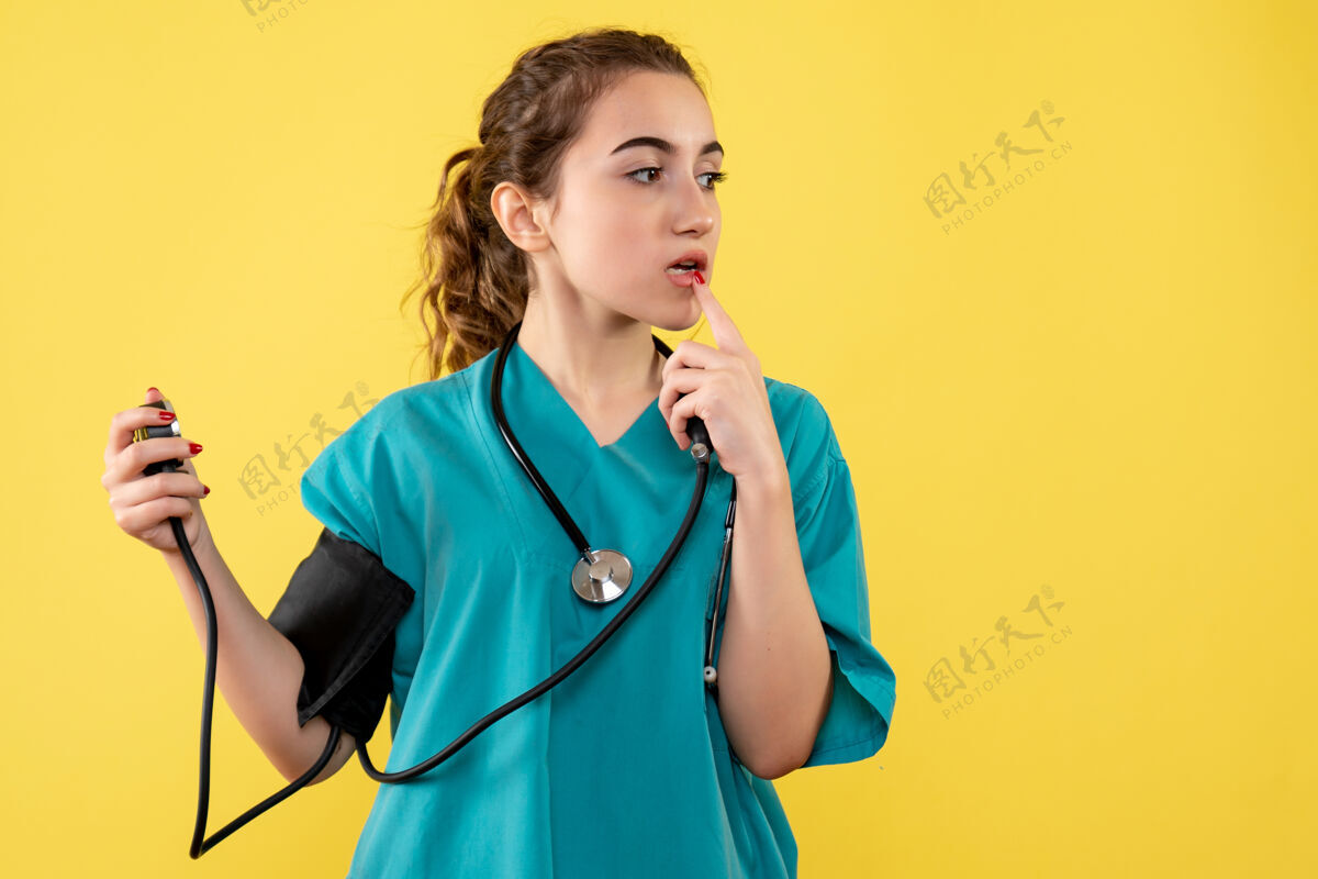 大流行前视图穿着医用衬衫的女医生正在检查她的压力 病毒健康情绪covid-19大流行医学黄色听诊器