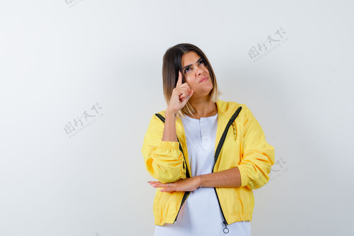 肖像身穿白色t恤 黄色夹克的年轻女孩用尤里卡手势举起食指 看上去很懂事 正对着前方看手势护理时尚