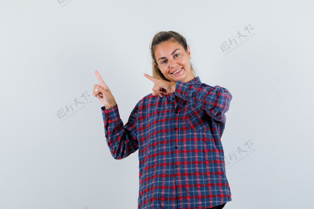 指穿着格子衬衫的年轻女子用食指指着左上角 看上去很高兴快乐格子自然