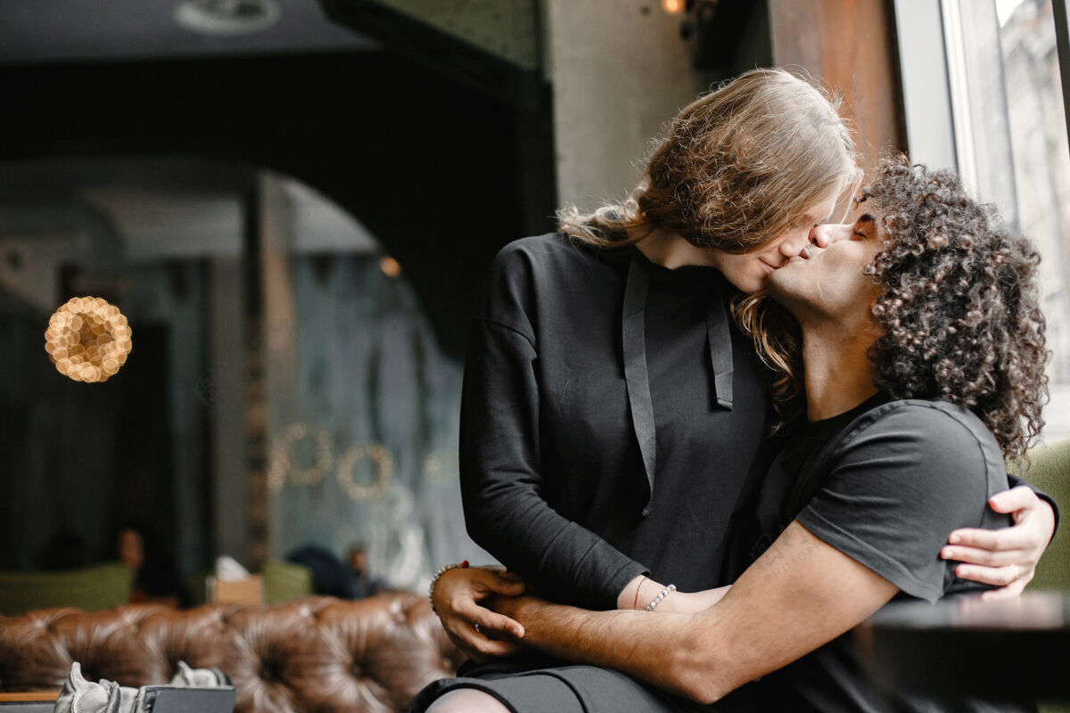 卷发一对年轻的情侣在咖啡馆里拥抱亲吻女人休闲休闲