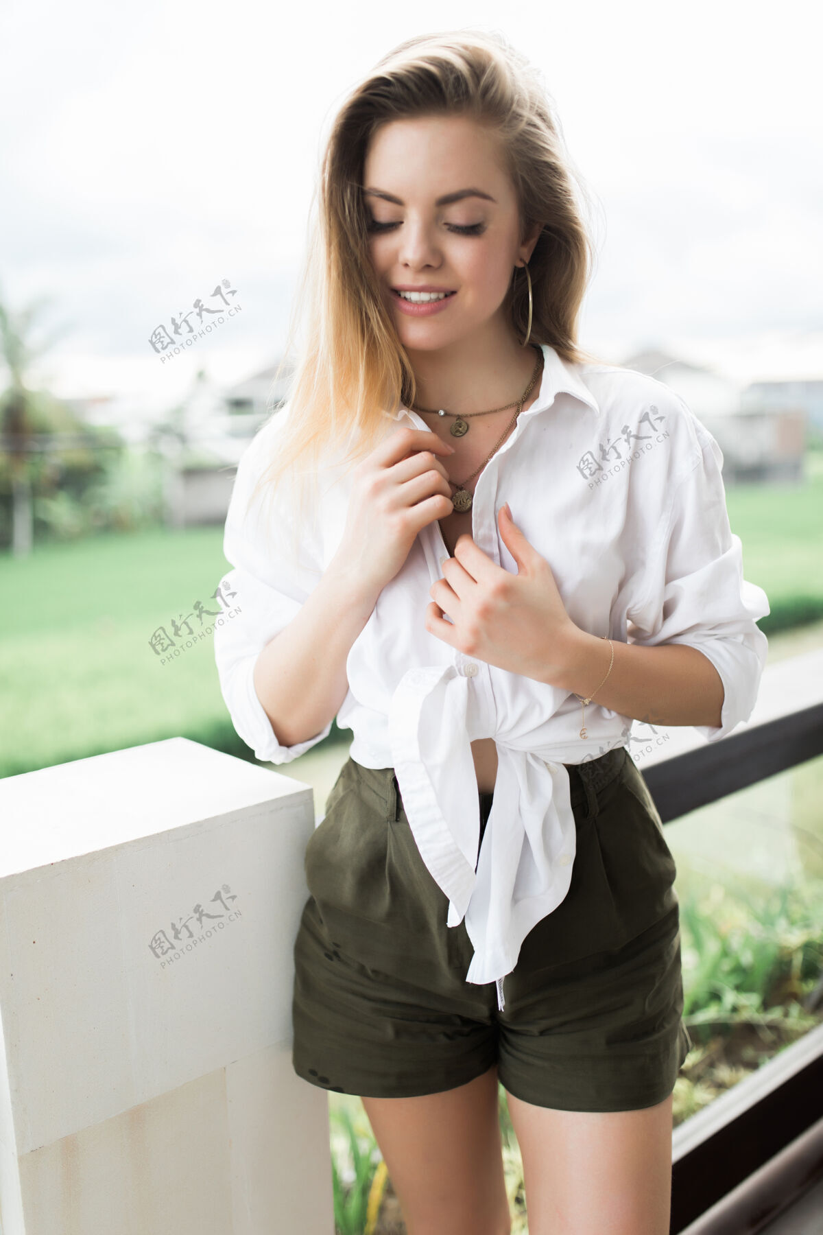 休闲年轻的女人站在阳台上向前看一个苗条的女人正在阳台上休息可爱享受华丽