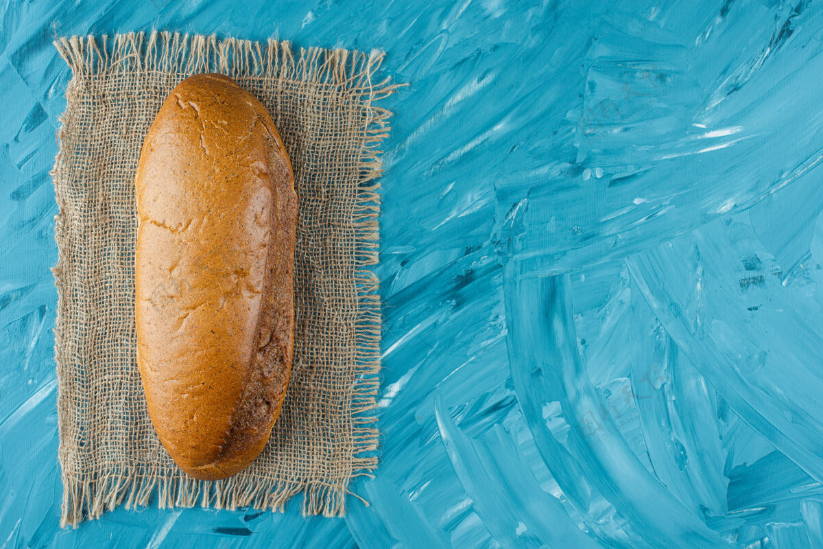 面包一整条白色的新鲜面包放在蓝色背景的麻布上小麦健康白面包