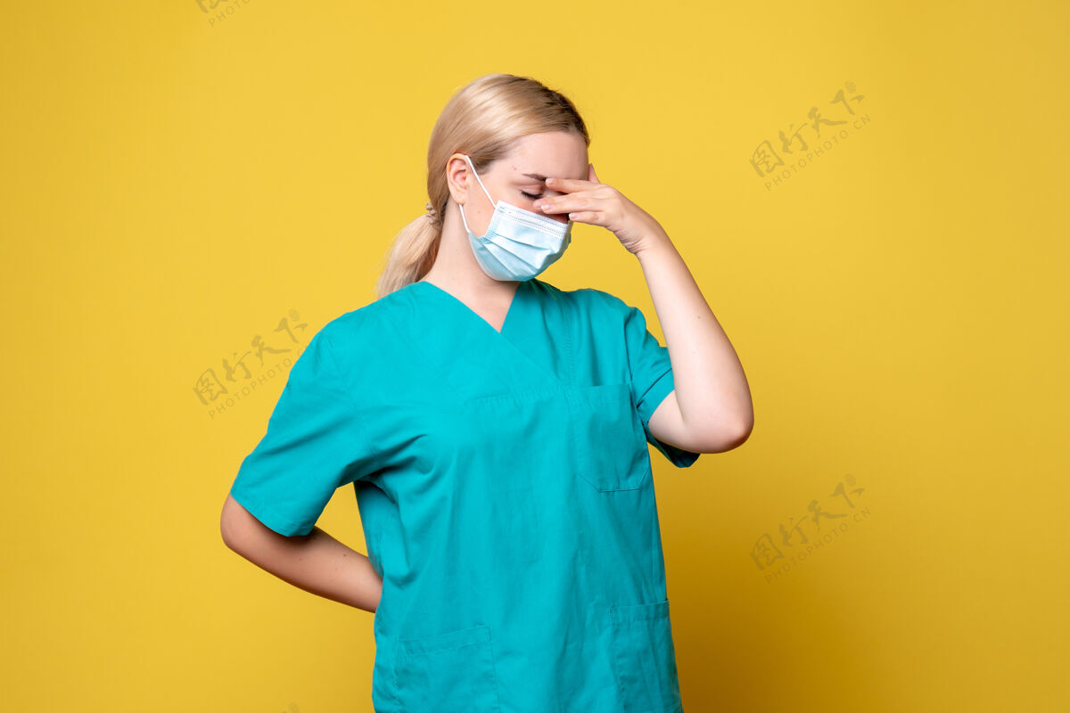 面具身穿医用衬衫和无菌口罩的年轻女医生正面图黄色墙壁上有压力感人表情成人