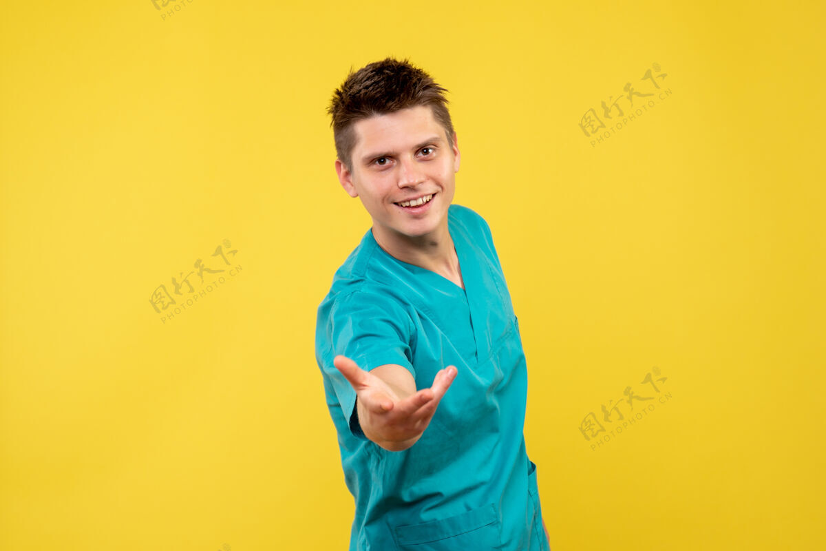 人黄色墙壁上穿着医疗服的男医生的正视图快乐西装成人