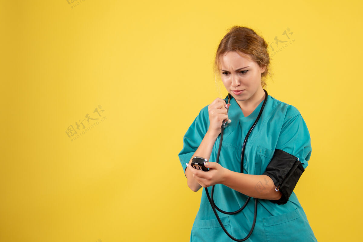 医疗器械身穿医疗服的女医生在黄色墙壁上检查压力的正视图人健康压力