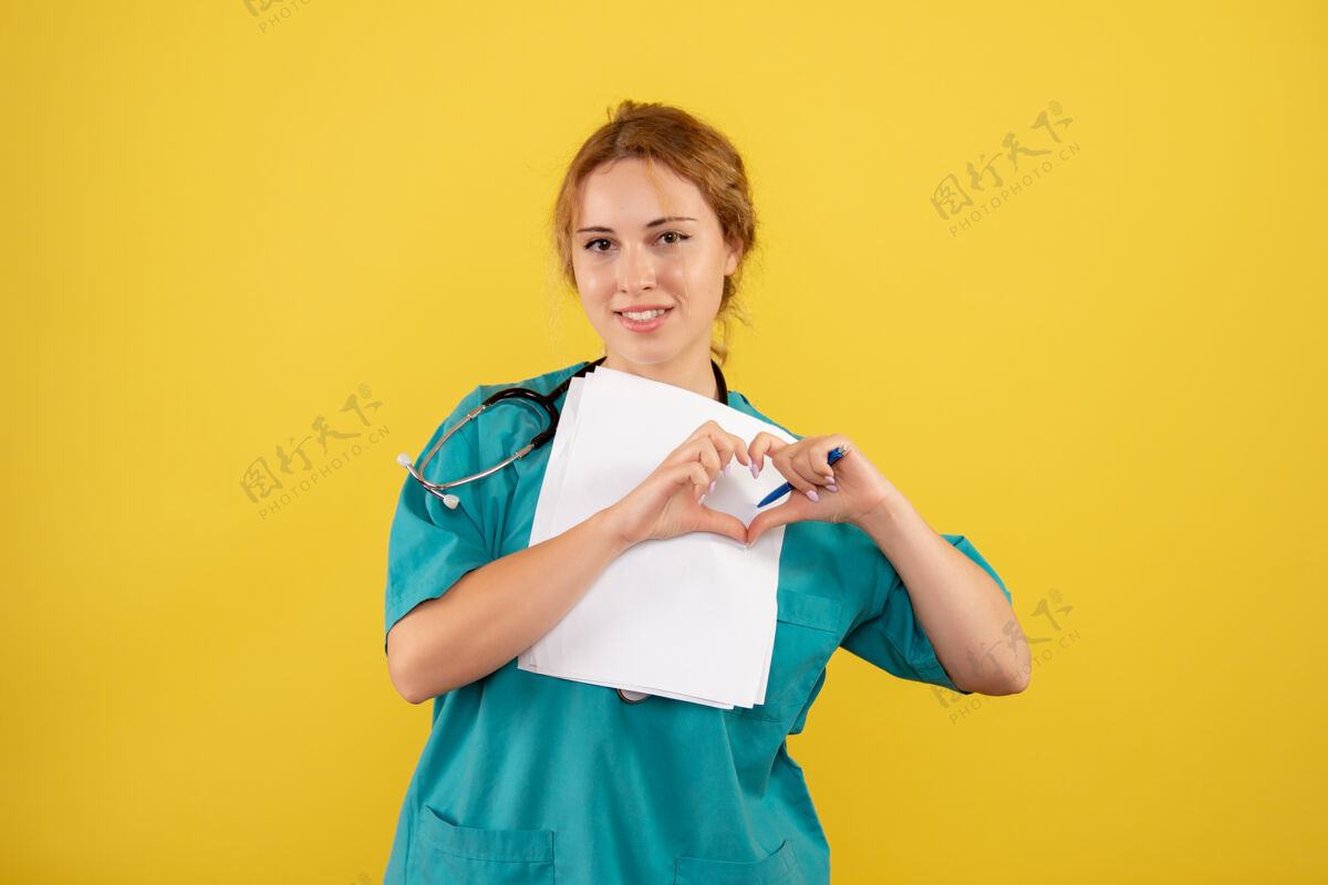 病毒黄色墙壁上穿着医疗服的女医生手持分析的正面图前面女医生快乐