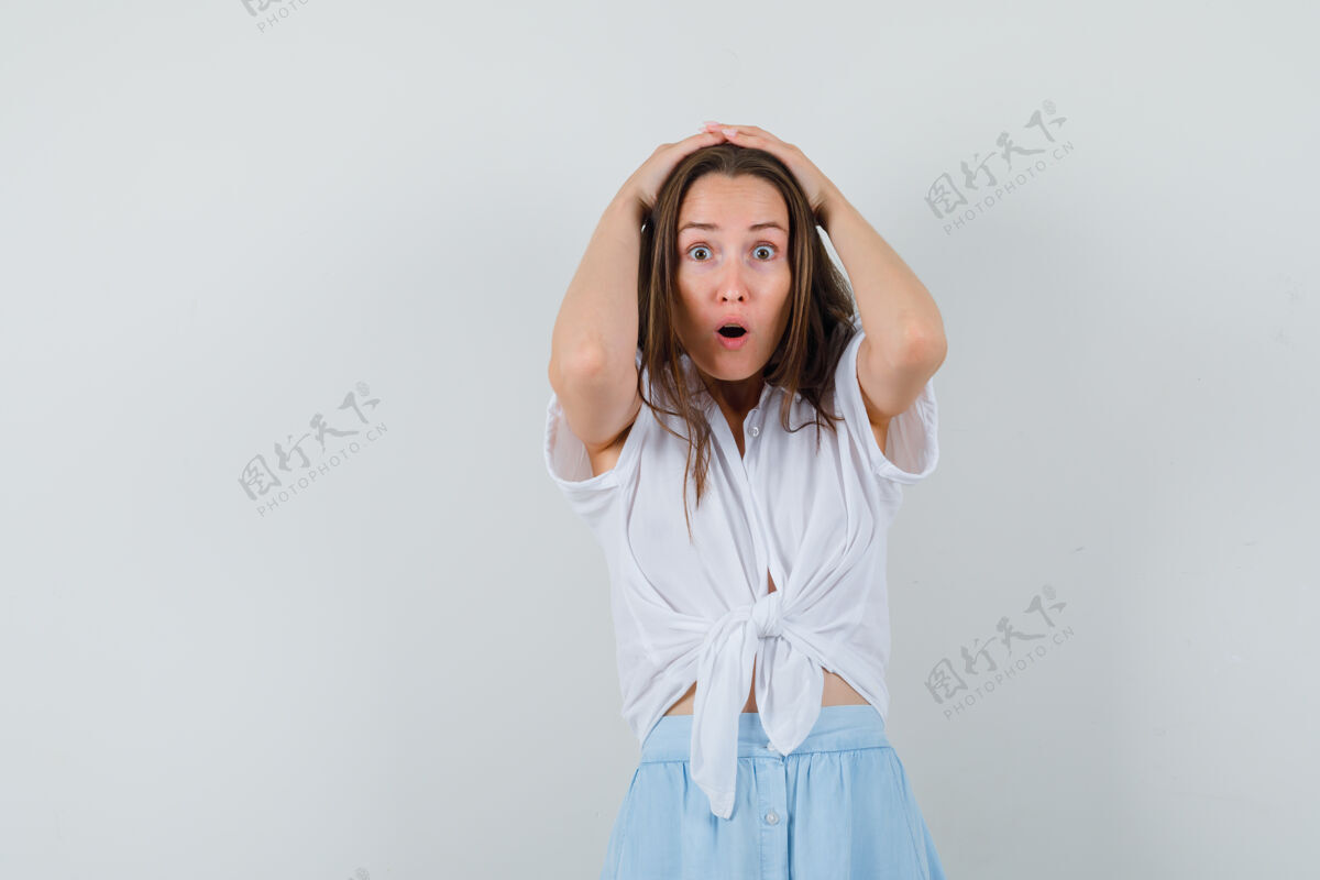 自然一个年轻的女人 手举着头 穿着白衬衫和淡蓝色的裙子 看起来很惊讶手头部女人