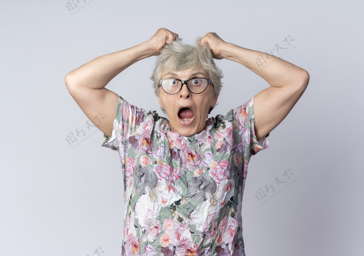 老戴着眼镜的震惊的老妇人举着头发 看起来像隔离在白墙上女人举举