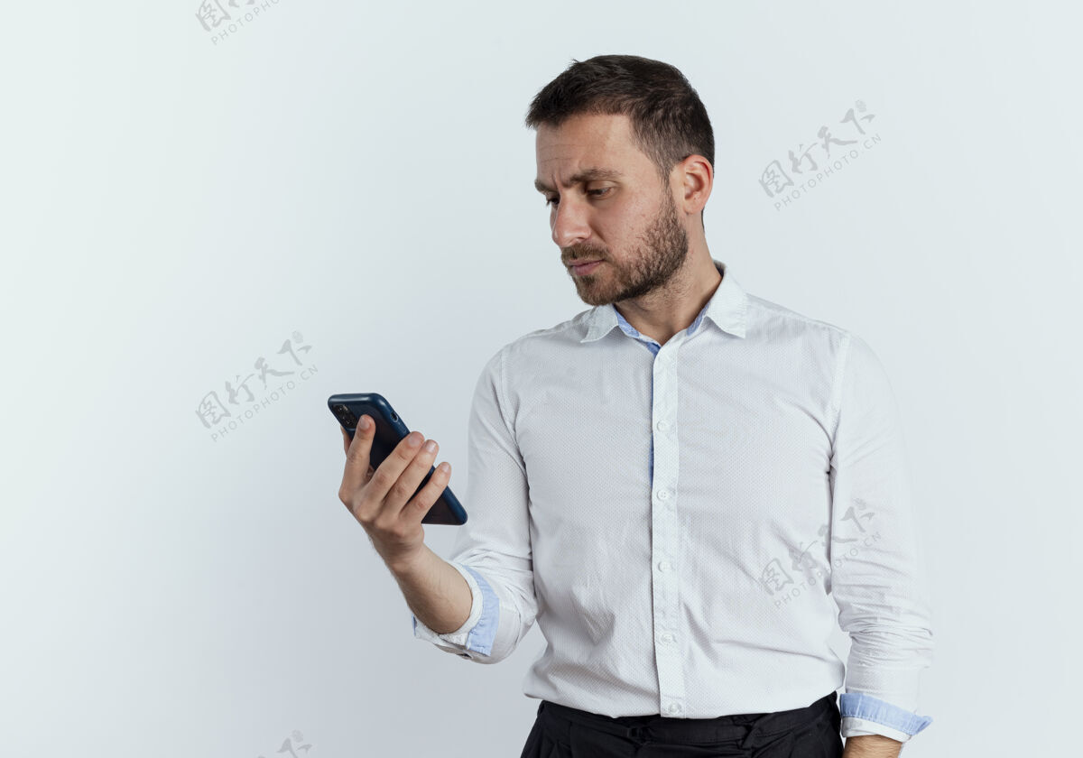严肃严肃的帅哥拿着手机 看着隔离在白墙上的手机男人人年轻