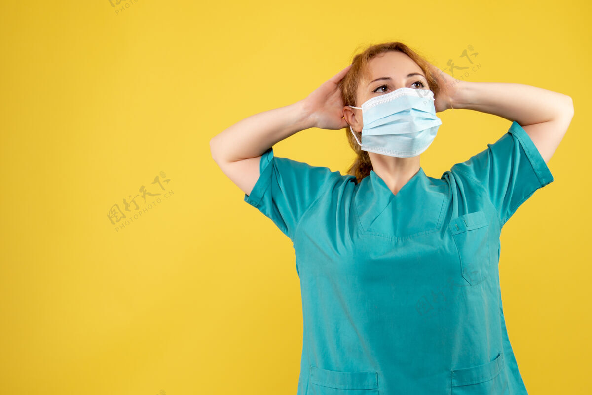 人黄墙上年轻女医生穿着医疗服 戴着无菌口罩的正面图医学套装漂亮