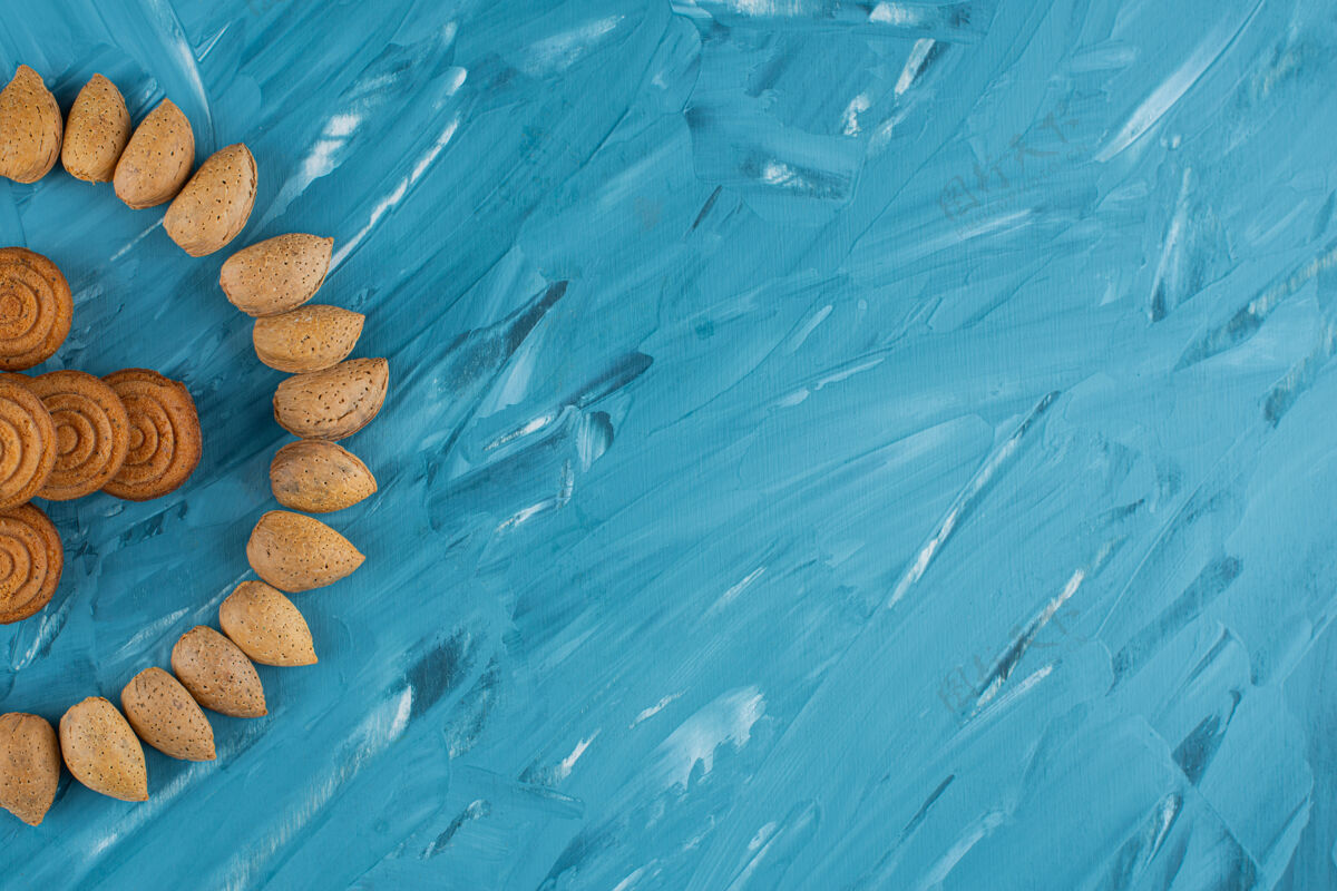 黄色一圈杏仁和新鲜甜甜的圆形饼干 背景是蓝色的生的杏仁健康