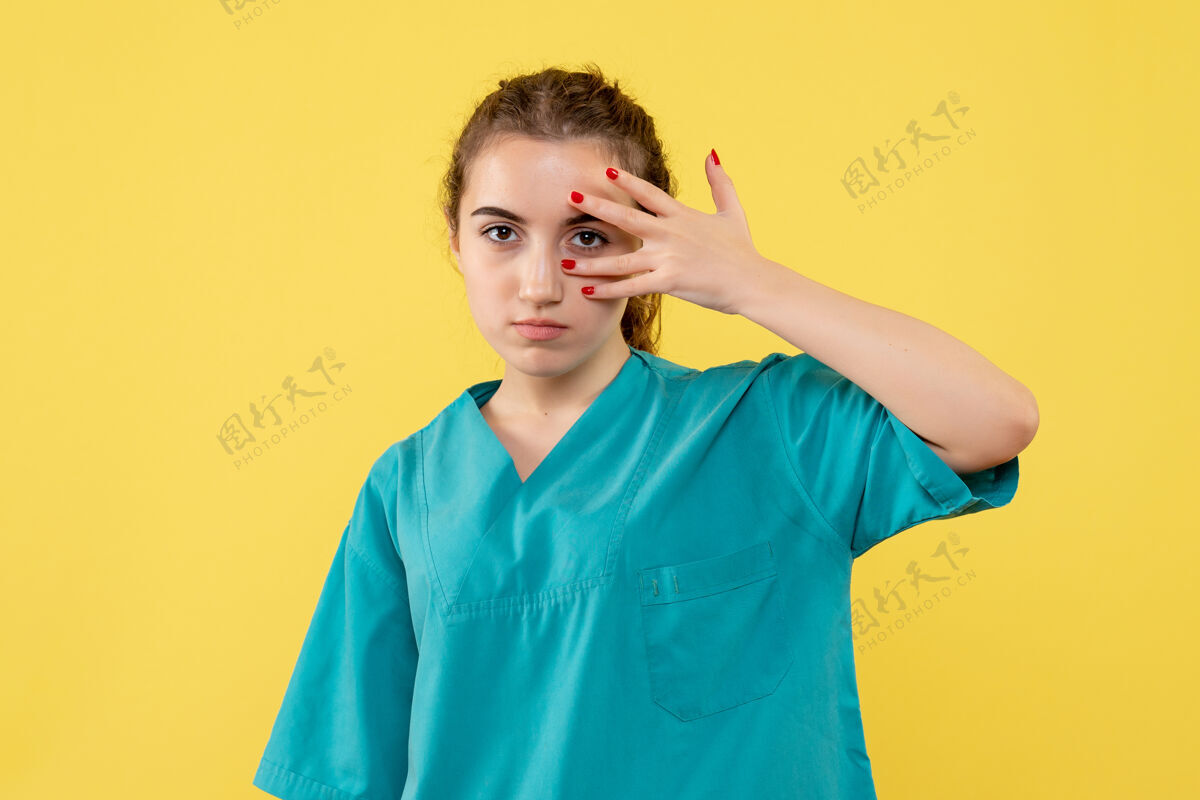 健康黄色墙壁上穿着医疗服的女医生的正视图医院医疗流行病