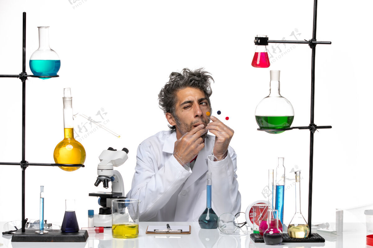 视图正面图：男科学家拿着样品放在桌子前 白色桌子上放着解决方案冠状病毒健康实验室的covid实验室人成人
