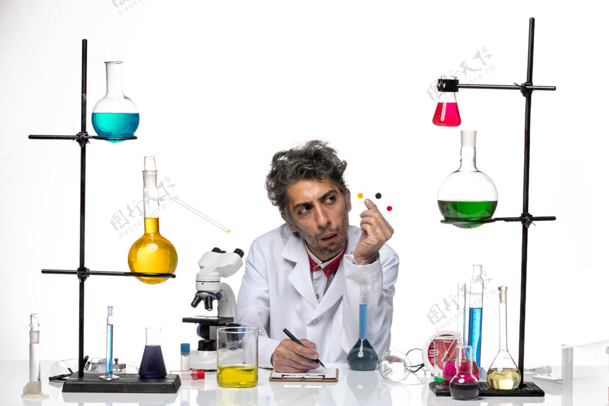专业人员正面图男性科学家拿着样品在桌子前 白色背景上的解决方案冠状病毒健康实验室covid药品保持解决方案