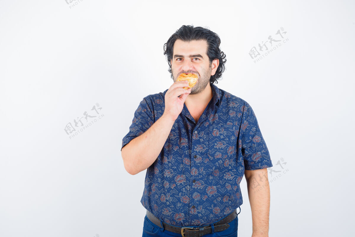 肖像成熟的男人一边吃糕点产品 一边看着相机里的衬衫 看着欣喜若狂 眼前一亮休闲男性前台
