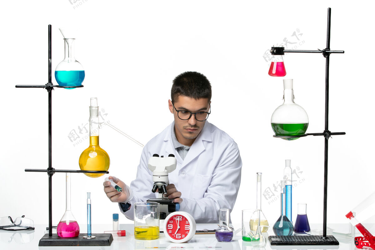 科学前视图穿着白色医疗服的男性化学家在白色背景的病毒科学实验室里用显微镜工作烧杯病毒罐子
