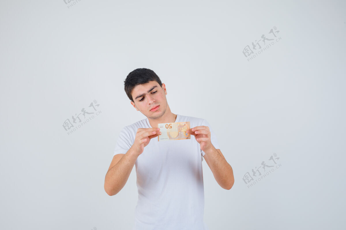 模特年轻的男性展示着穿着t恤的欧洲钞票 看上去很小心 正面视图人消磨时间男人